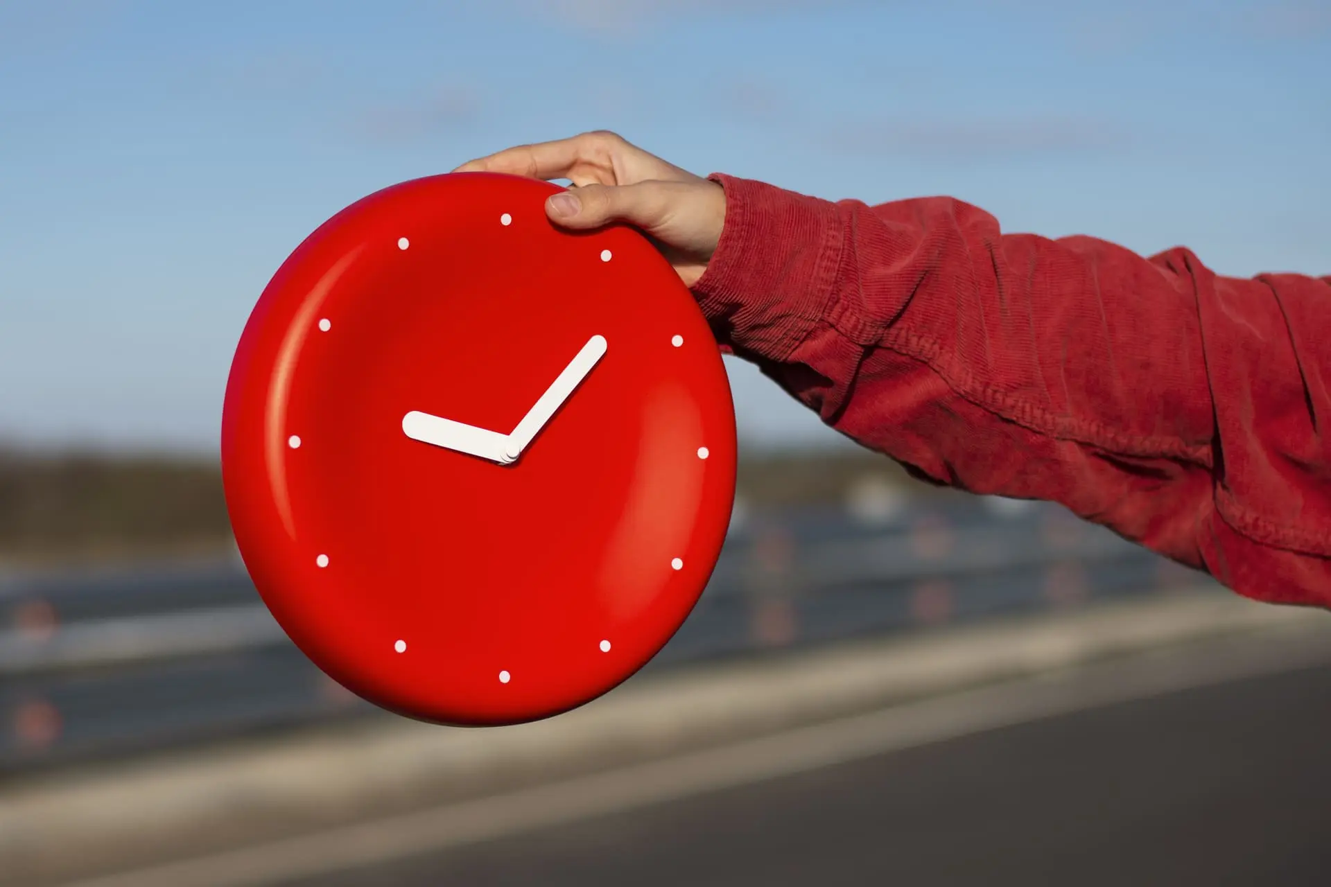 Main tenant une horloge murale rouge